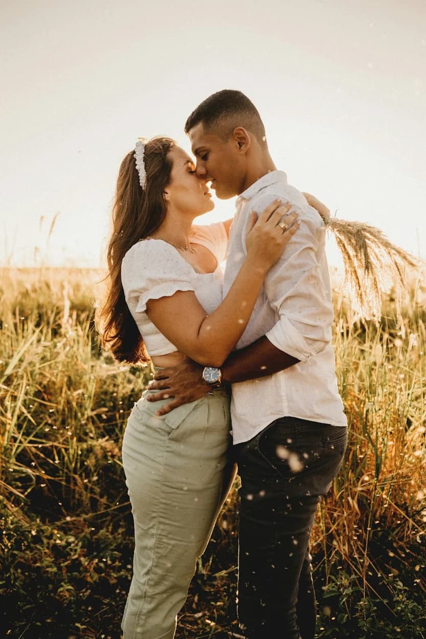 Couple embracing in a sunlit field of tall grass — illustrative style reference